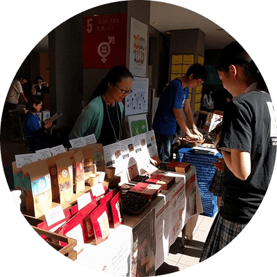 商品を販売する人とそれを見ている人の写真