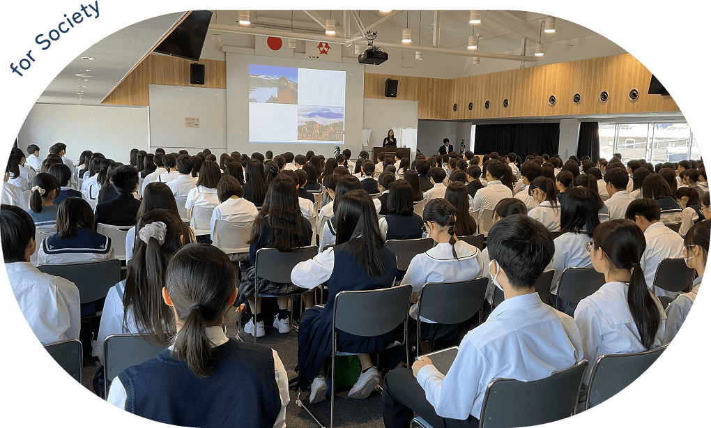 制服を着た学生たちが講演を聞いている写真