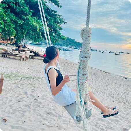 海岸でブランコに乗る女性の写真