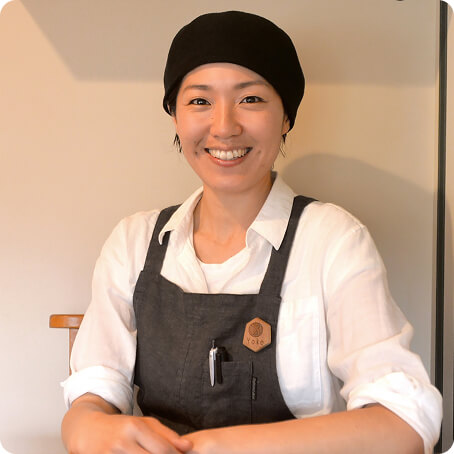 お店のエプロン姿で笑う女性の写真