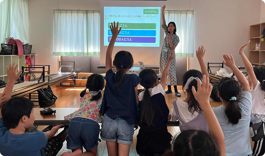 手を挙げている子どもたちと前に立って手を挙げる代表の写真