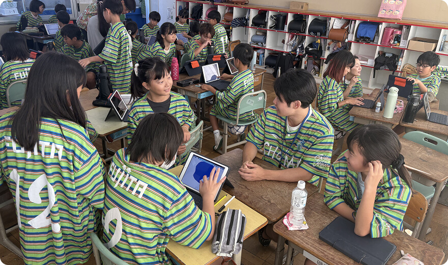 同じユニフォームをきた子どもたちがチームでタブレットを操作したり話したりしている写真
