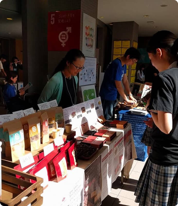 商品を販売する人とそれを見ている人の写真