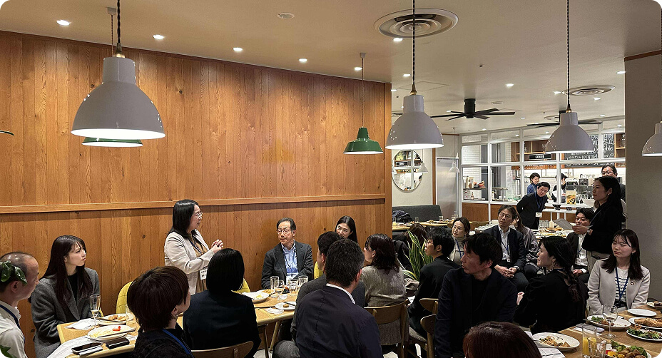 食事の前に女性の話を聞く人たちの写真