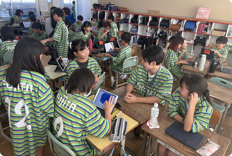 教室で同じユニフォームを着て話し合う人たちの写真