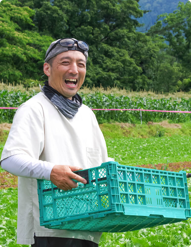布のバッグから野菜を取り出す男性と、その野菜を持つ後ろ姿の女性の写真