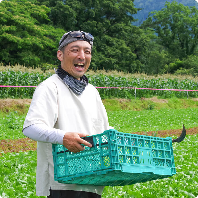 畑でコンテナを持つ笑顔の男性の写真