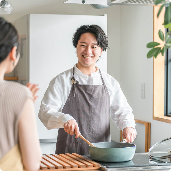 フライパンで料理を作る笑顔の男性の写真
