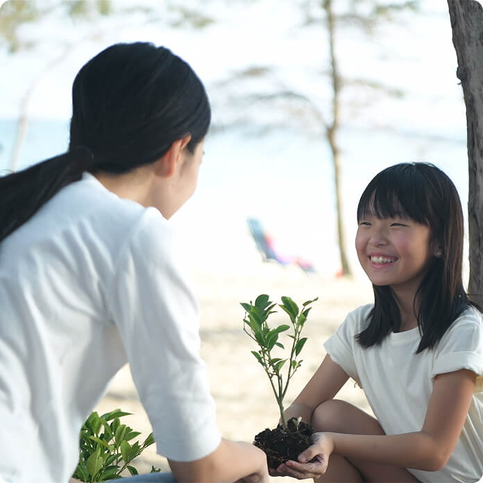 苗木を持って女性に微笑む女の子の写真