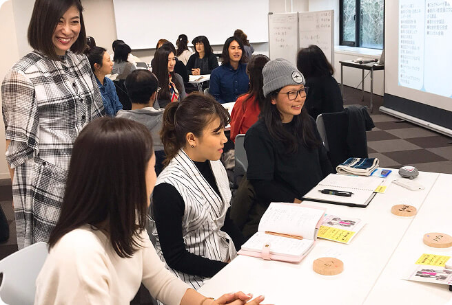 テーブルで話をしている人たちとそれを笑顔で見守る代表の写真