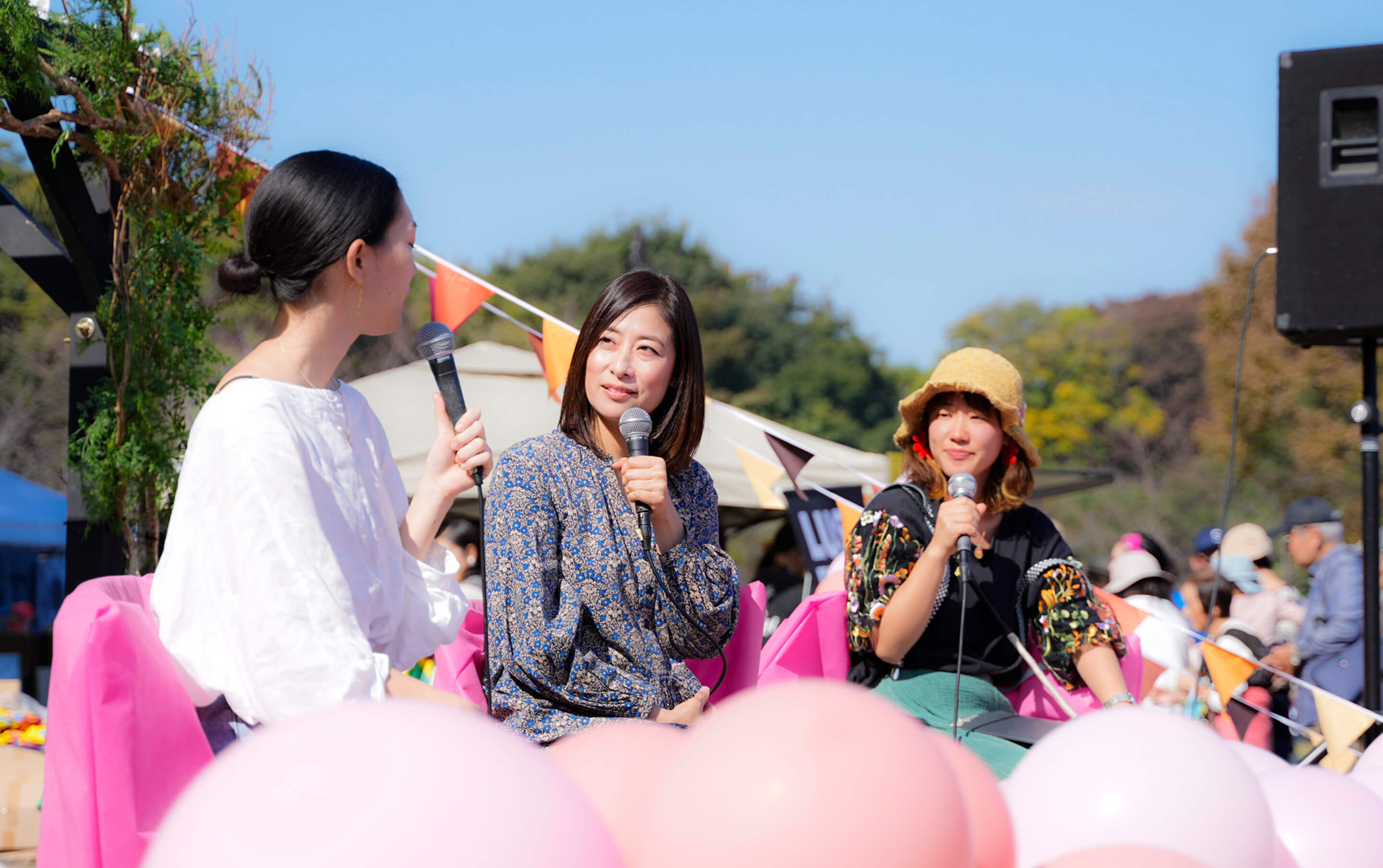 屋外で講演をする代表と女性2人の写真